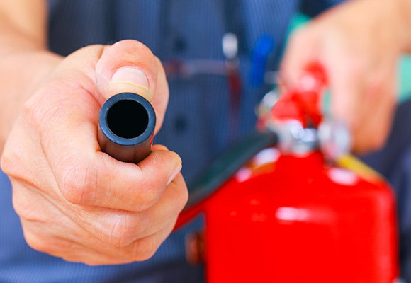 hand holding the hose of a fire extinguisher demonstrating fire safety measures and equipment for emergencies