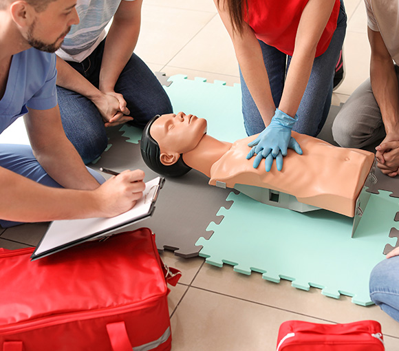 individuals practicing CPR on a training mannequin with a first aid kit nearby demonstrating emergency response skills 3 techniques 3 lifesaving 3 training