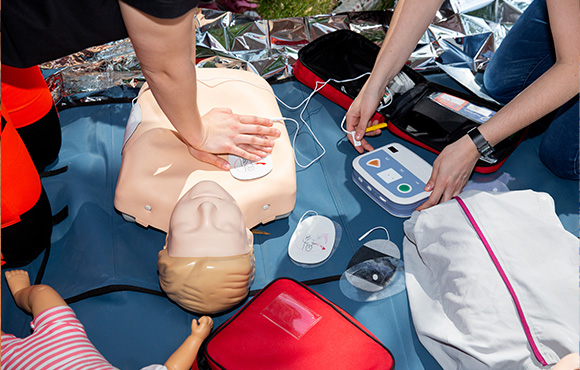 people performing CPR on a training mannequin with medical equipment and first aid supplies demonstrating lifesaving techniques for emergencies including basic life support and first aid training