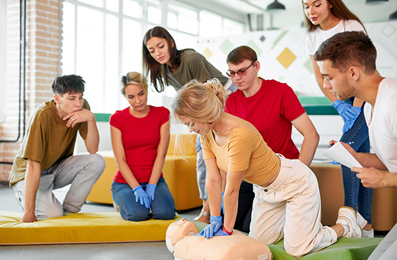 group of people practicing CPR on a manikin in a training session emphasizing first aid techniques and teamwork for effective assistance