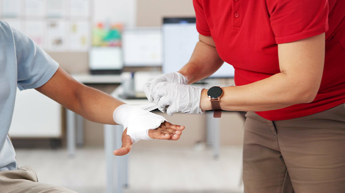 person receiving first aid treatment for hand injury with bandages and medical assistance in background first aid techniques for safety and health 8 bandages 8 care